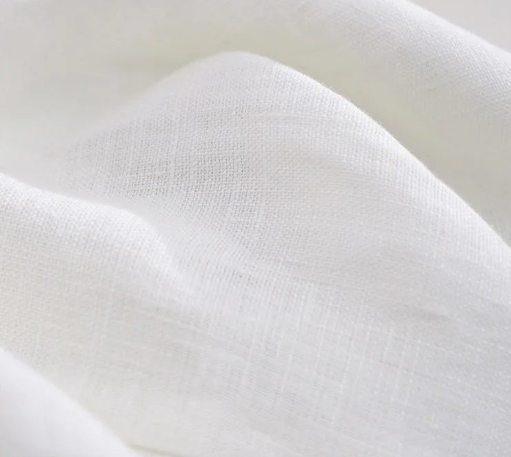 Close-up of white linen fabric, showcasing its soft texture, perfect for summer clothing | SuzzaneMarket.