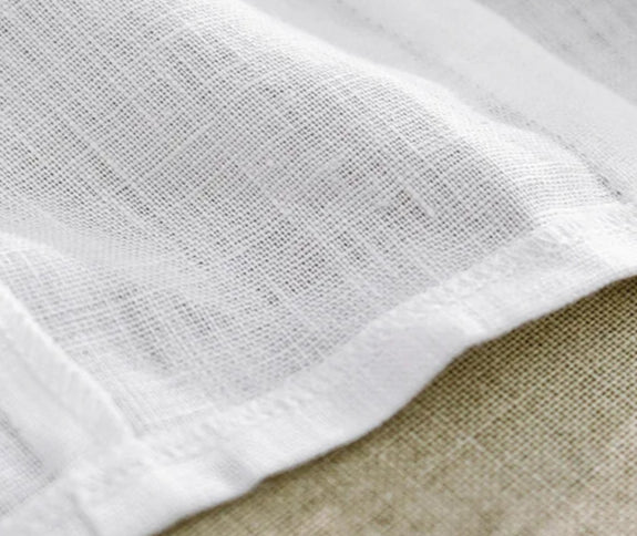 Close-up of white linen fabric demonstrating its lightweight texture and subtle weave, perfect for summer wear | SuzzaneMarket