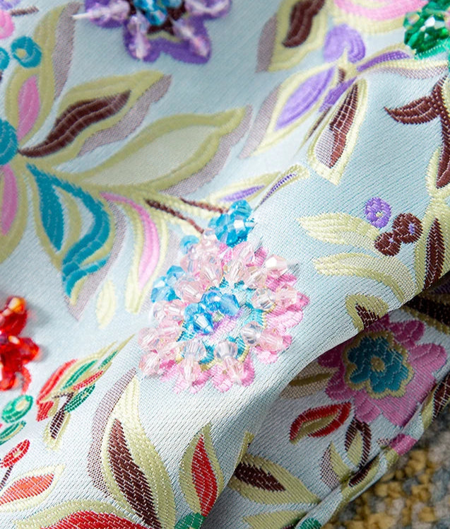 Close-up of colorful floral jacquard fabric with embroidery and sequins, highlighting intricate details. | SuzzaneMarket