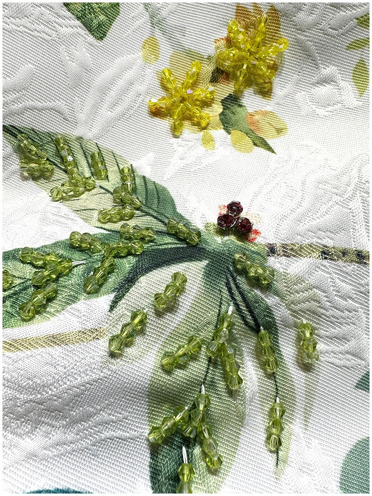 Détails broderie en perles et pierres sur tissu blanc avec motif floral | SuzzaneMarket