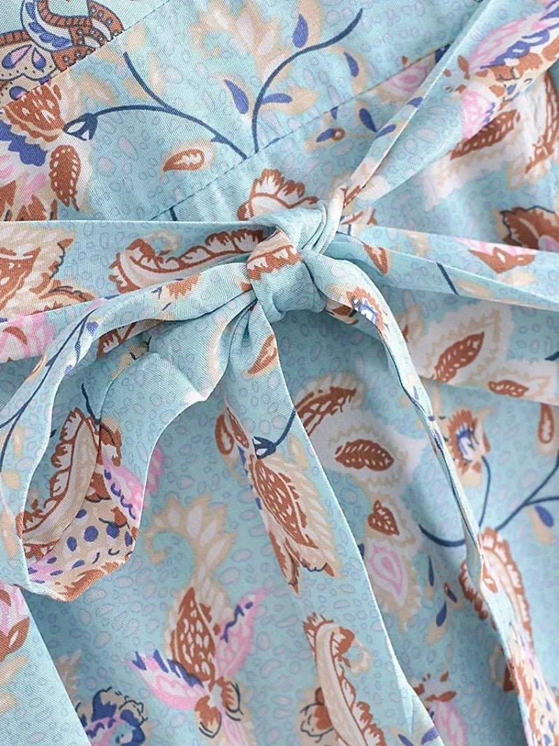 Close-up of the tie detail on a light blue bohemian beach robe featuring floral patterns and a matching belt.