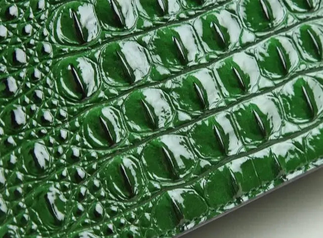 Texte en cuir croco vert, texture brillante et luxueuse, parfaite pour le Sac Messenger Cuir Croco -THAU- de SuzzaneMarket.