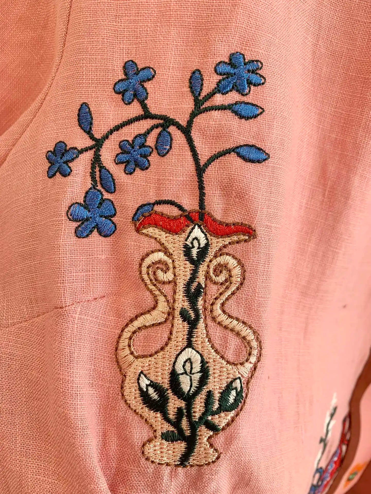 Close-up of pink fabric with detailed floral embroidery featuring a vase design | SuzzaneMarket