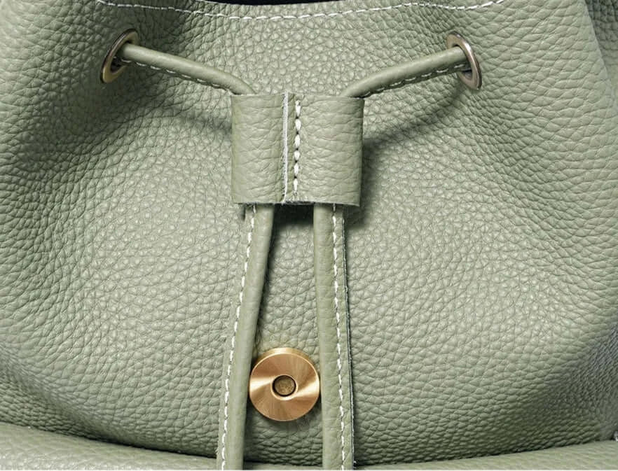 Détail du sac à dos en cuir grainé verde avec cordon et fermeture éclair, disponible sur Suzzanemarket.