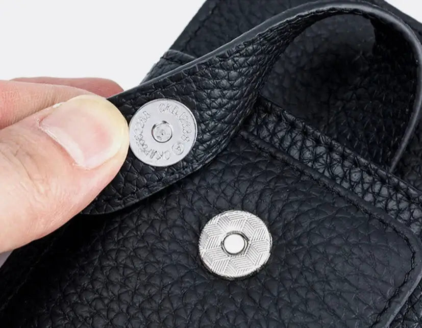 Close-up of the secure snap closure on a black grained leather phone pouch by CYLA.
