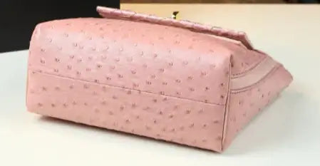 Sac rétro cuir autruche rose demi-souple avec fermeture rabat et boucle. Disponible chez SuzzaneMarket.