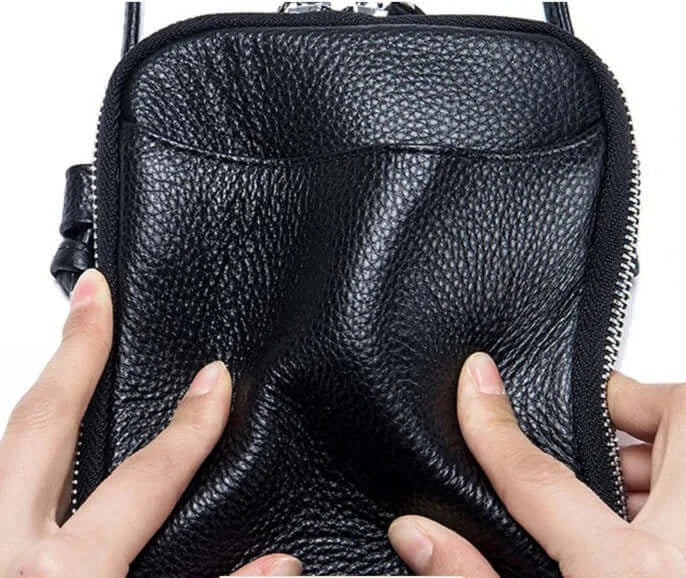 Sac pochette cuir grainé noir avec fermeture à double zipper, tenue en main pour un look élégant et pratique.