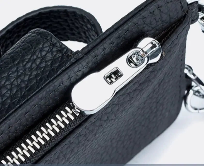 Close-up of black grained leather phone pouch zip with silver hardware, showcasing practical design for cards and cash.
